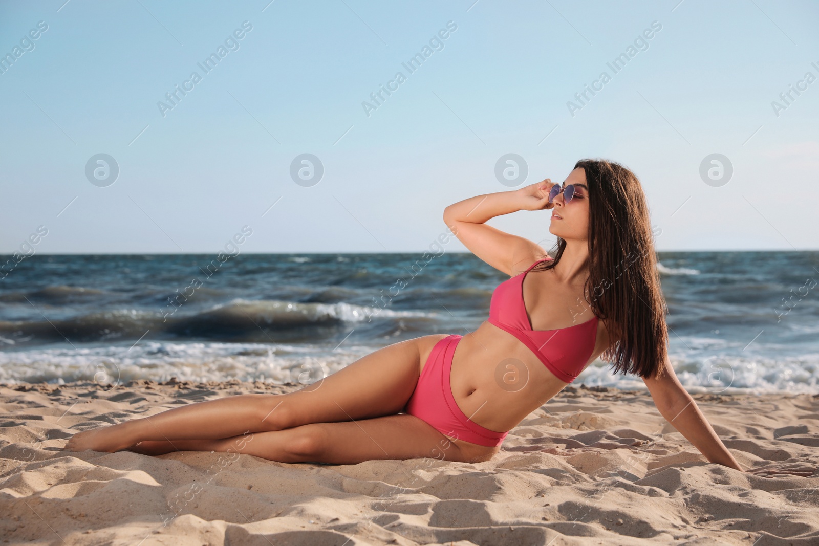 Photo of Beautiful young woman with attractive body posing on sandy beach
