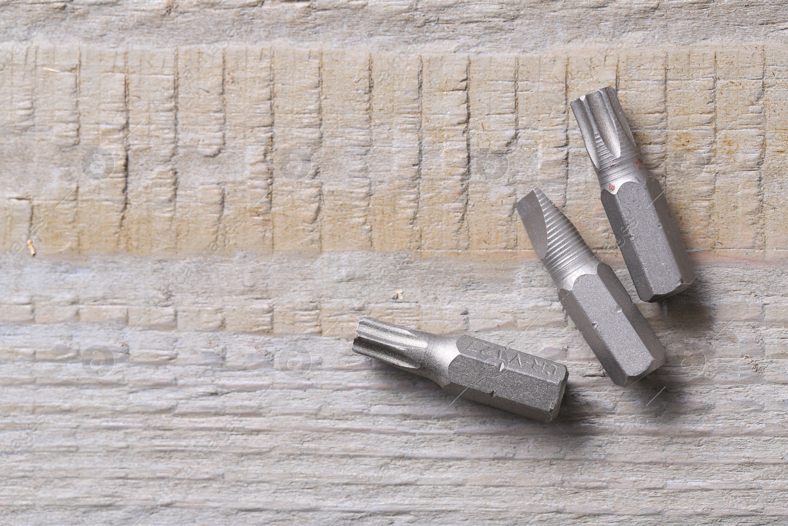 Photo of Different screwdriver bits on wooden table, top view