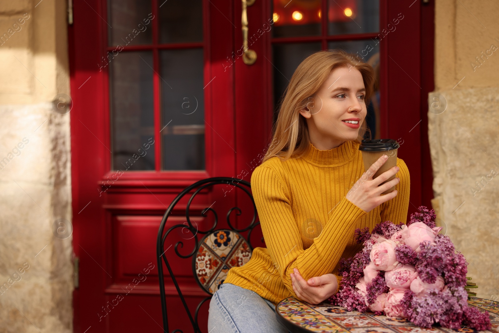 Photo of Beautiful woman with bouquet of spring flowers and coffee in outdoor cafe, space for text