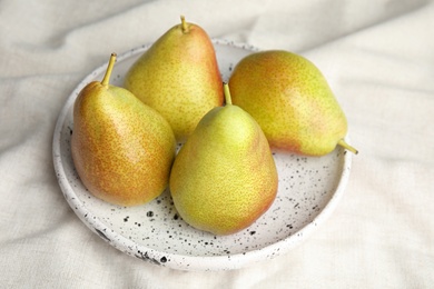 Photo of Plate with ripe juicy pears on light fabric