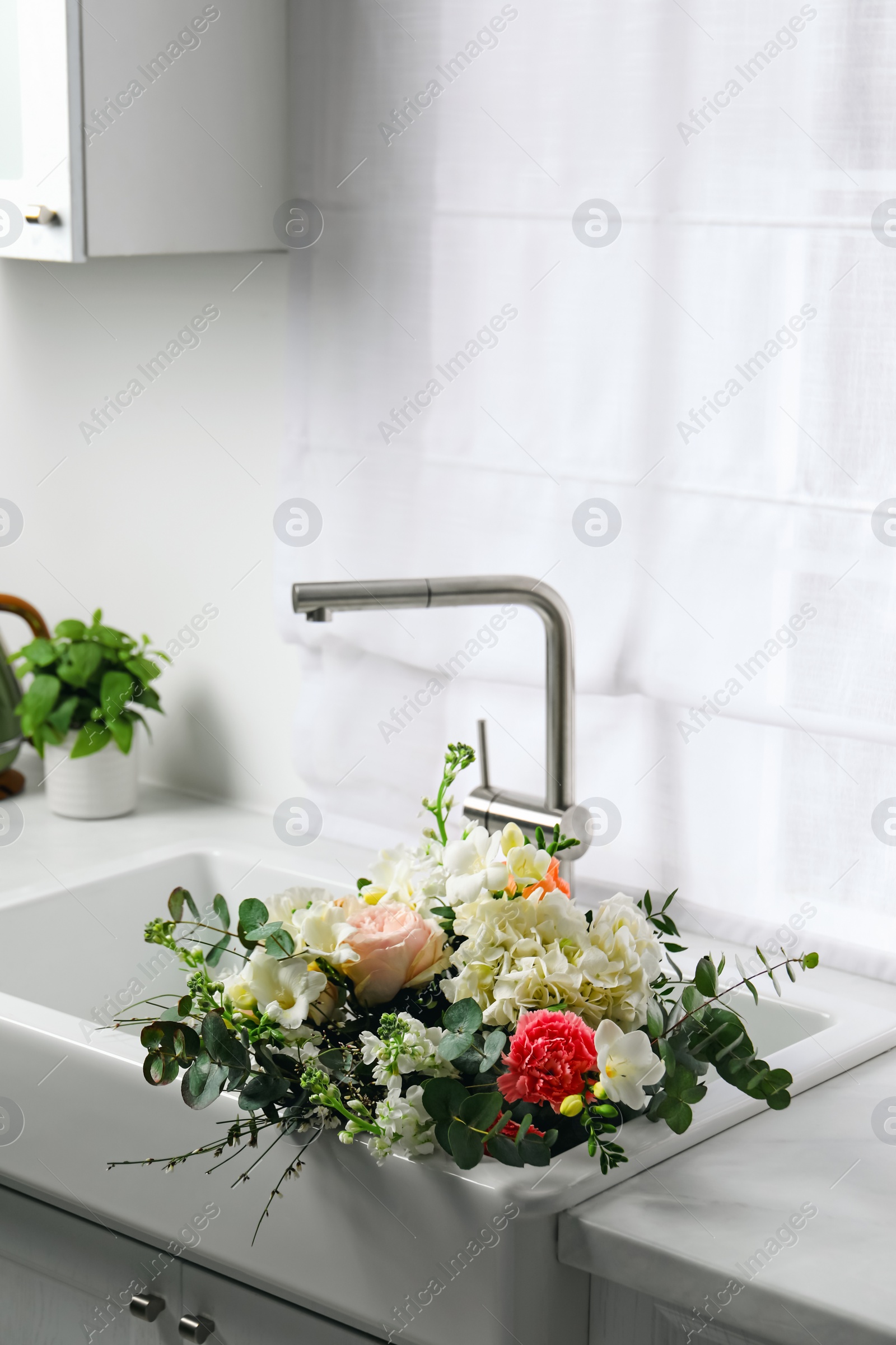 Photo of Bouquet of beautiful flowers in kitchen sink