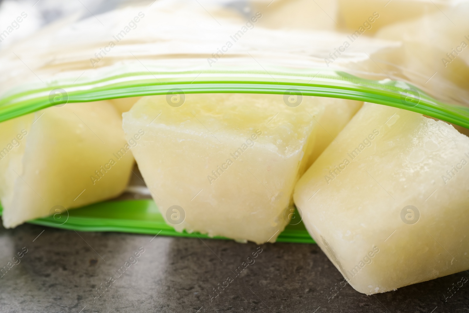 Photo of Frozen cauliflower puree cubes in plastic bag on grey table, closeup