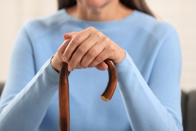 Photo of Mature woman with walking cane indoors, closeup