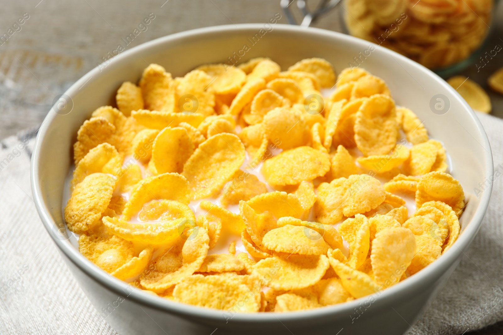 Photo of Tasty crispy corn flakes with milk in bowl, closeup