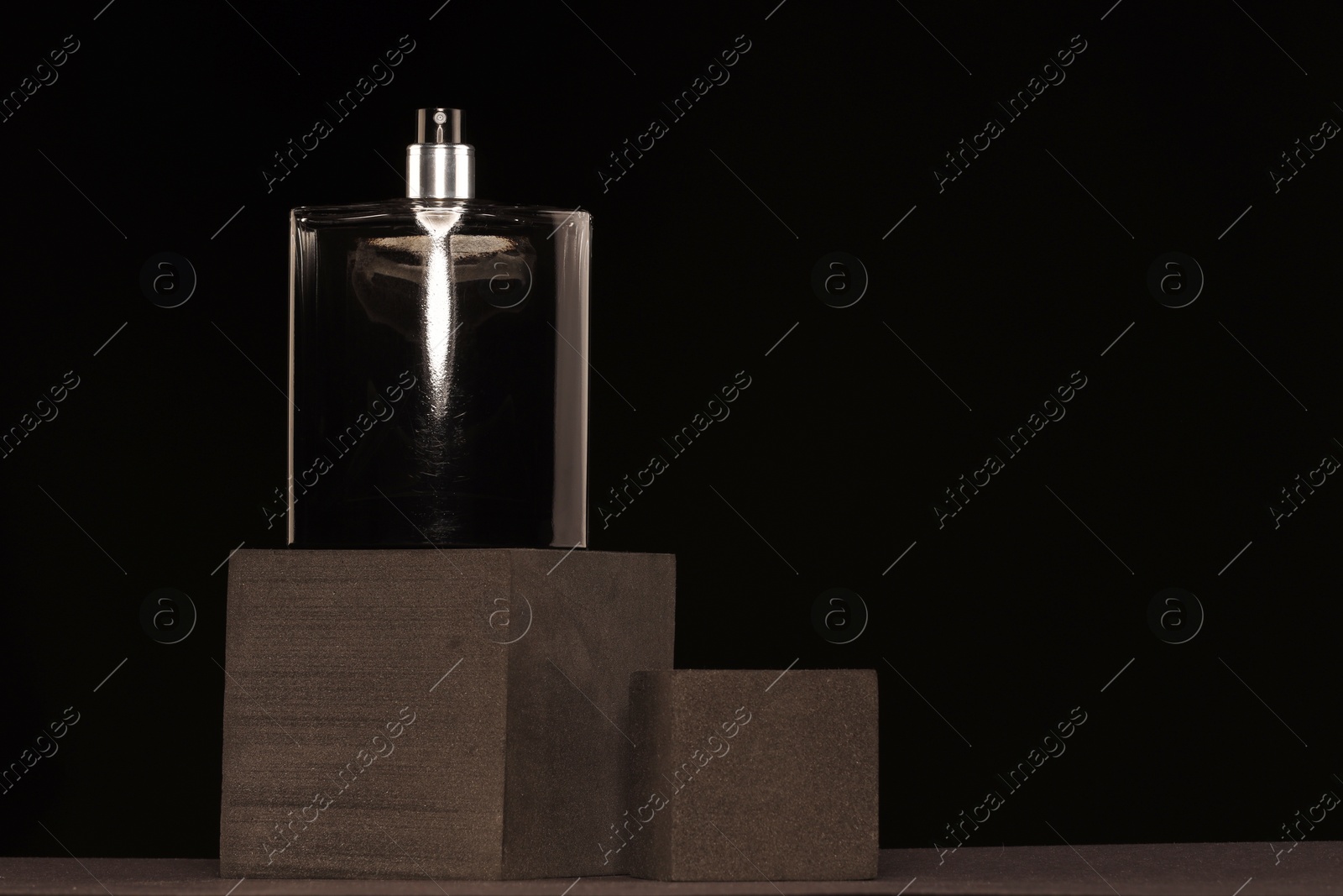 Photo of Luxury men`s perfume in bottle against black background, space for text