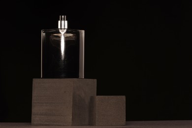 Luxury men`s perfume in bottle against black background, space for text