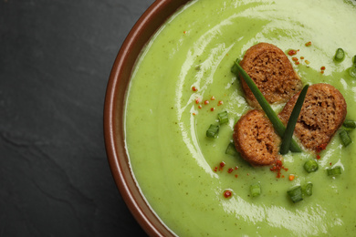 Photo of Tasty homemade zucchini cream soup on black table, top view