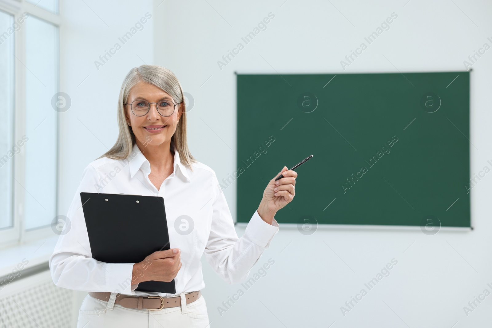 Photo of Portrait of happy professor with clipboard and pen in classroom, space for text