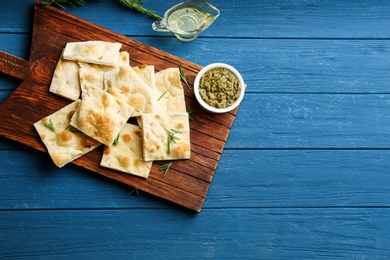 Photo of Delicious focaccia bread on blue wooden table, flat lay. Space for text