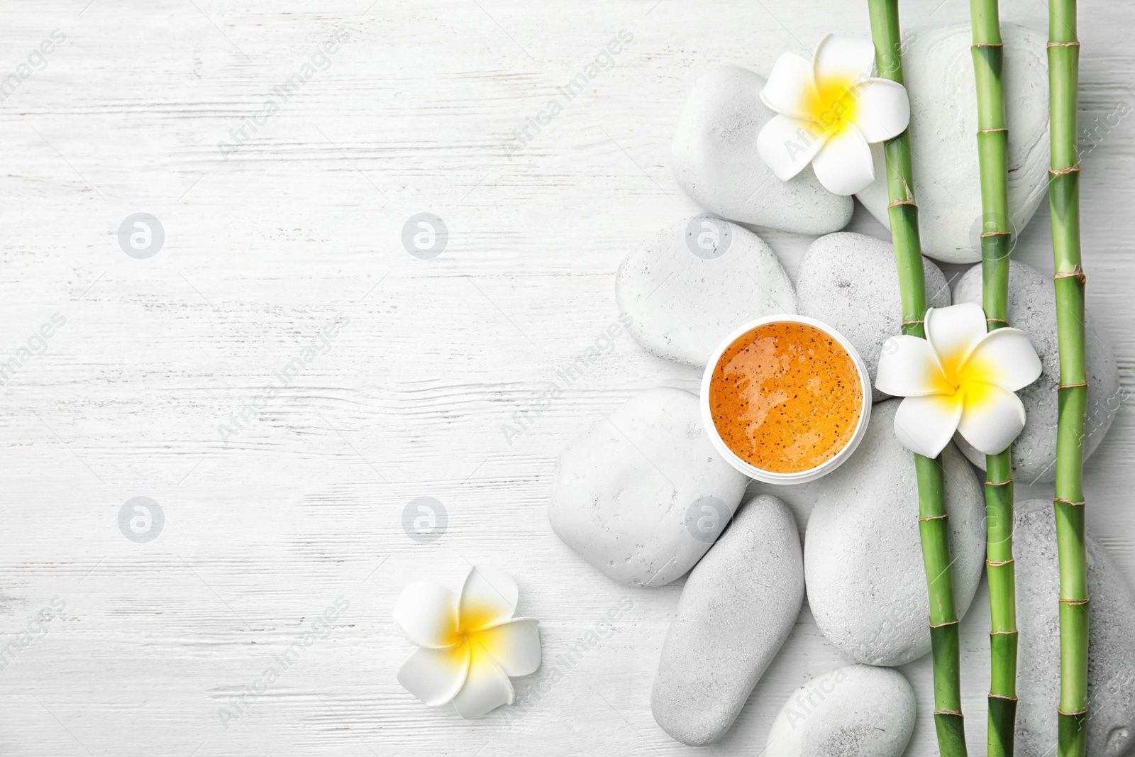 Photo of Flat lay composition with bamboo branches and spa stones on wooden background. Space for text