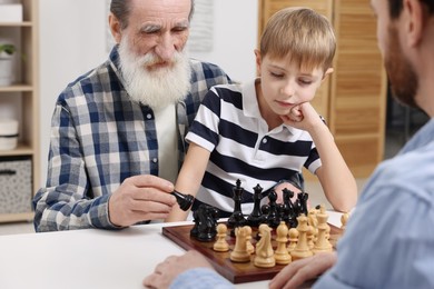 Family playing chess together at table in room