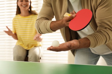 Photo of Man playing ping pong with friends indoors, closeup