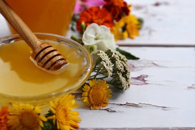 Photo of Honey with dipper in bowl and different flowers on white wooden table, closeup. Space for text