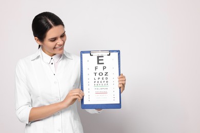 Photo of Ophthalmologist with vision test chart on light background, space for text