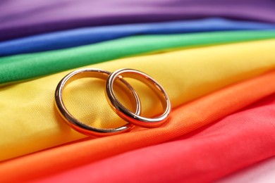 Wedding rings on rainbow LGBT flag, closeup