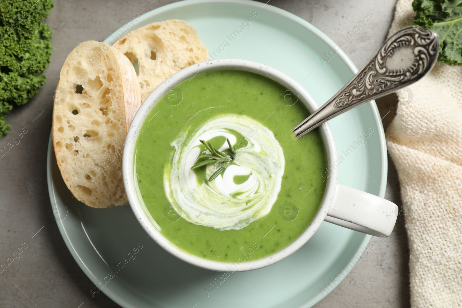 Photo of Tasty kale soup served on grey table, flat lay