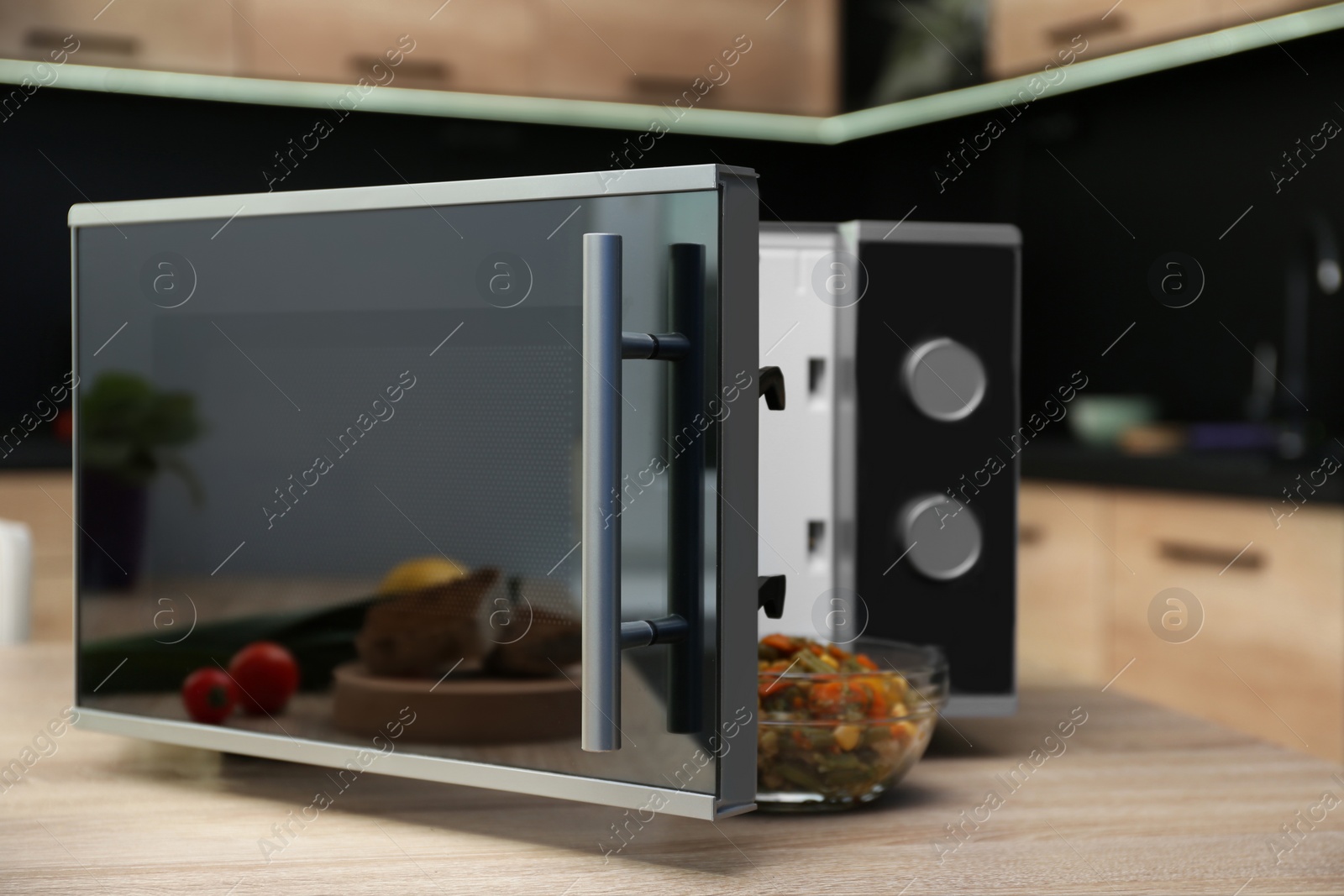 Photo of Open modern microwave oven on table in kitchen