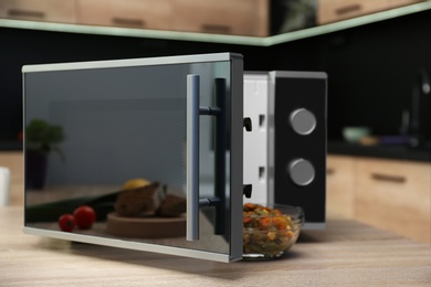 Photo of Open modern microwave oven on table in kitchen