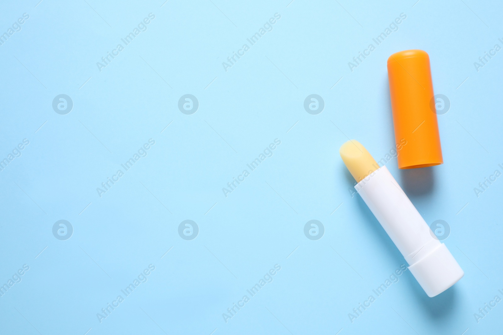 Photo of Hygienic lipstick on light blue background, flat lay. Space for text