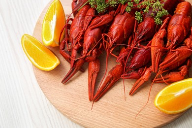 Photo of Delicious red boiled crayfish and orange on white wooden table, top view