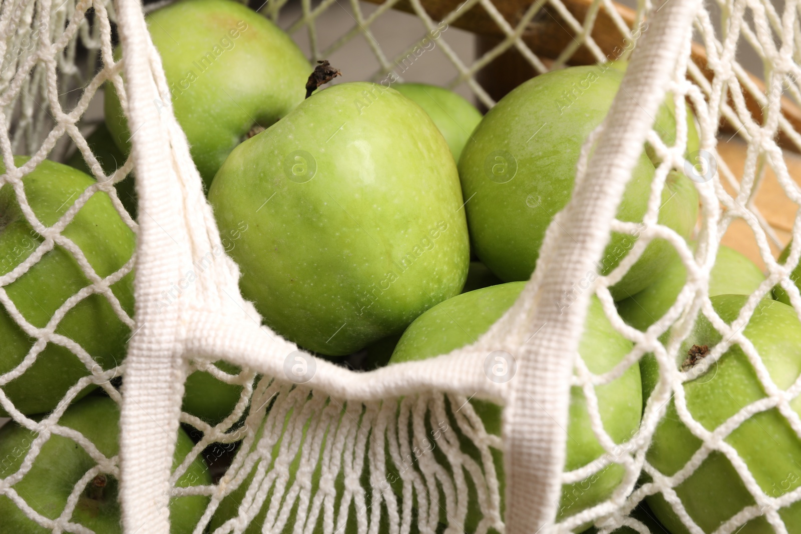 Photo of Fresh green apples in net bag, closeup