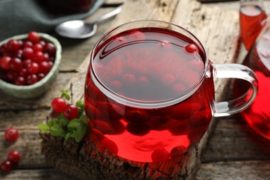 Photo of Delicious cranberry tea and berries on wooden table, closeup