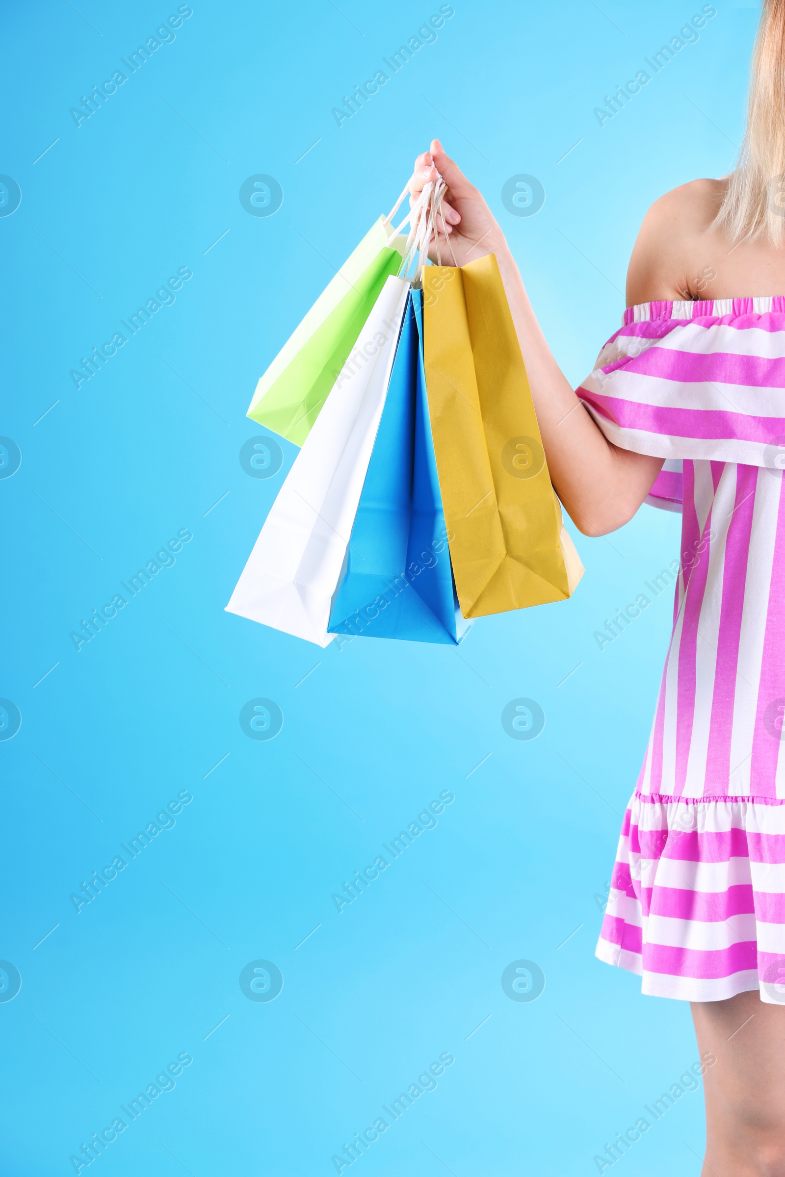 Photo of Young woman with shopping bags on color background, closeup