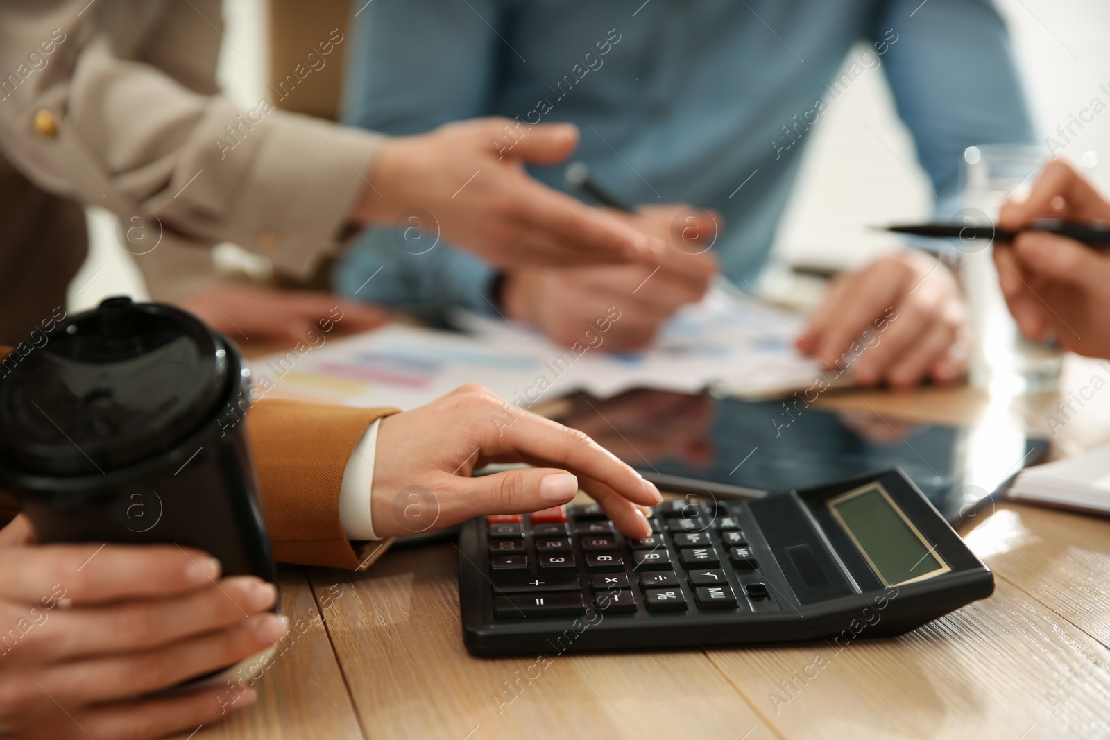 Photo of Woman using calculator at table in office during business meeting, closeup. Management consulting