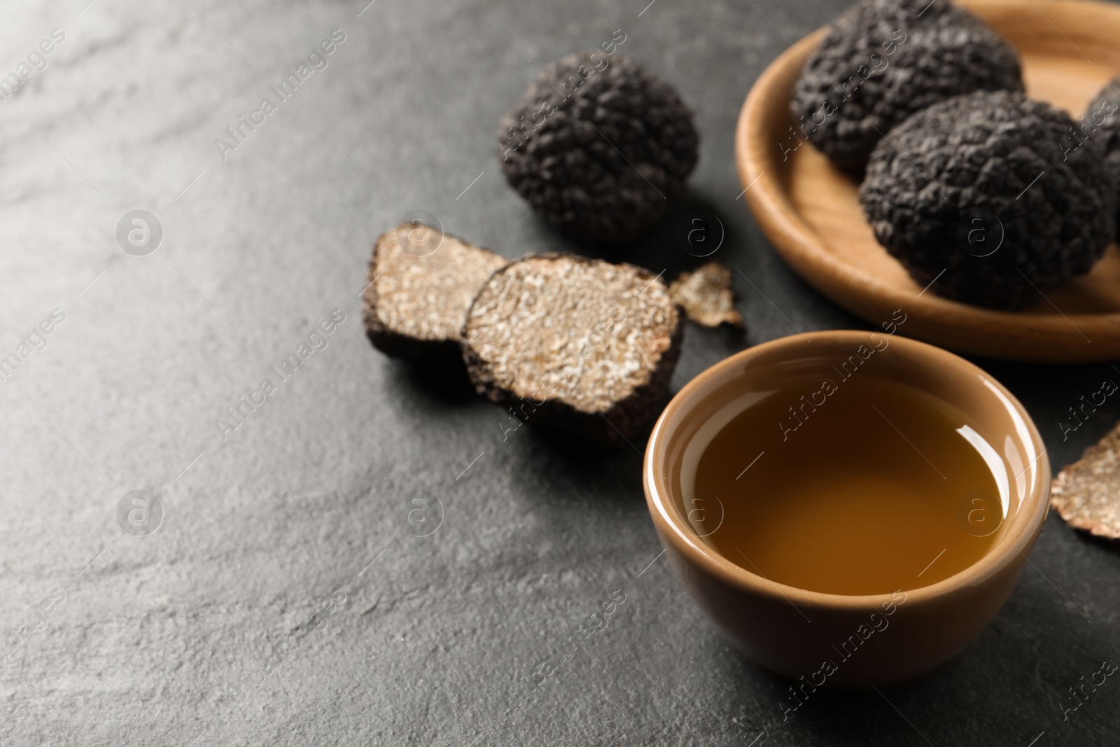 Photo of Bowl of truffle oil on grey table. Space for text