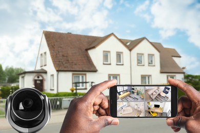 Image of Home security system. African American man monitoring modern CCTV cameras on smartphone near his house, closeup