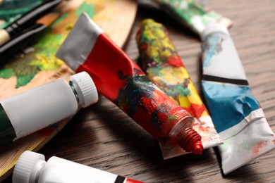 Photo of Tubes with oil paints on wooden table, closeup