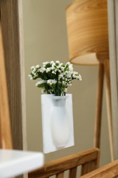 Silicone vase with beautiful white flowers on mirror in room