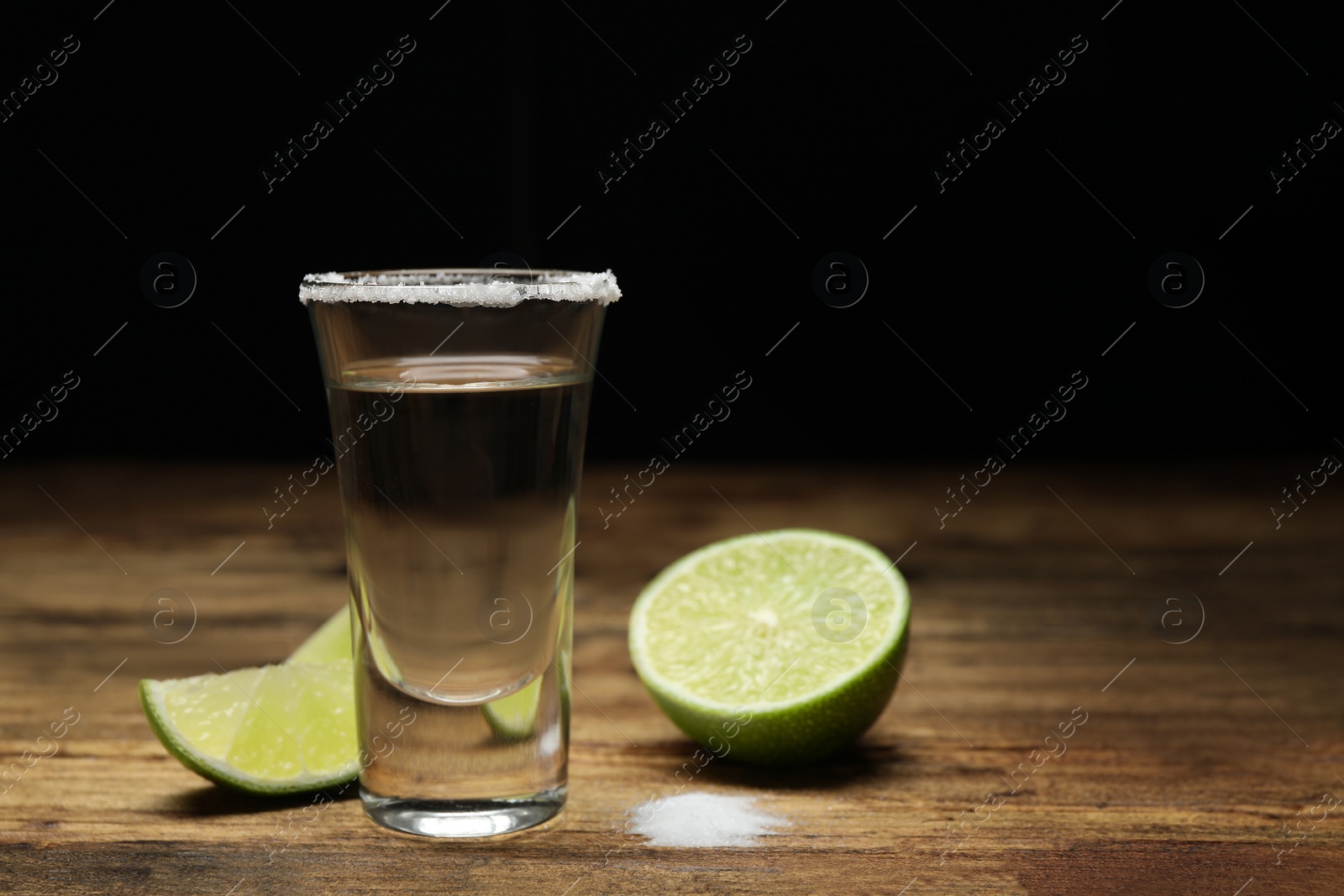 Photo of Mexican Tequila shot with salt and lime on wooden table. Space for text