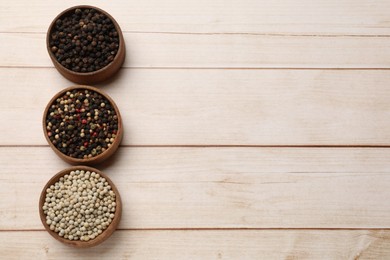 Photo of Aromatic spices. Different peppers in bowls on wooden table, flat lay. Space for text