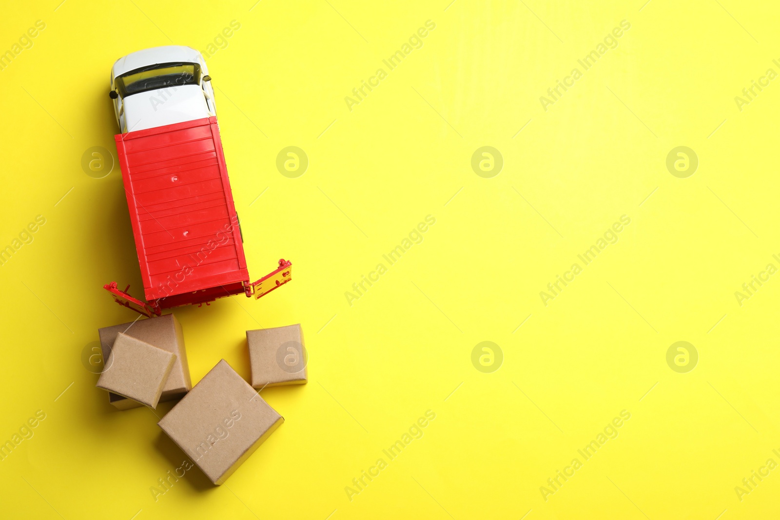 Photo of Top view of toy truck with boxes on yellow background, space for text. Logistics and wholesale concept