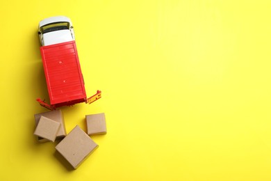 Photo of Top view of toy truck with boxes on yellow background, space for text. Logistics and wholesale concept
