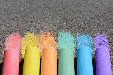 Photo of Colorful chalk sticks on asphalt outdoors, closeup. Space for text