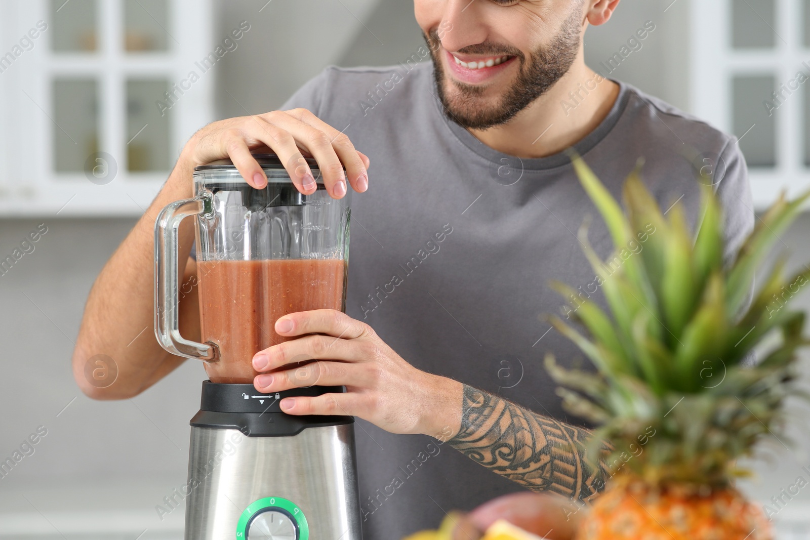 Photo of Man preparing tasty smoothie indoors, closeup view