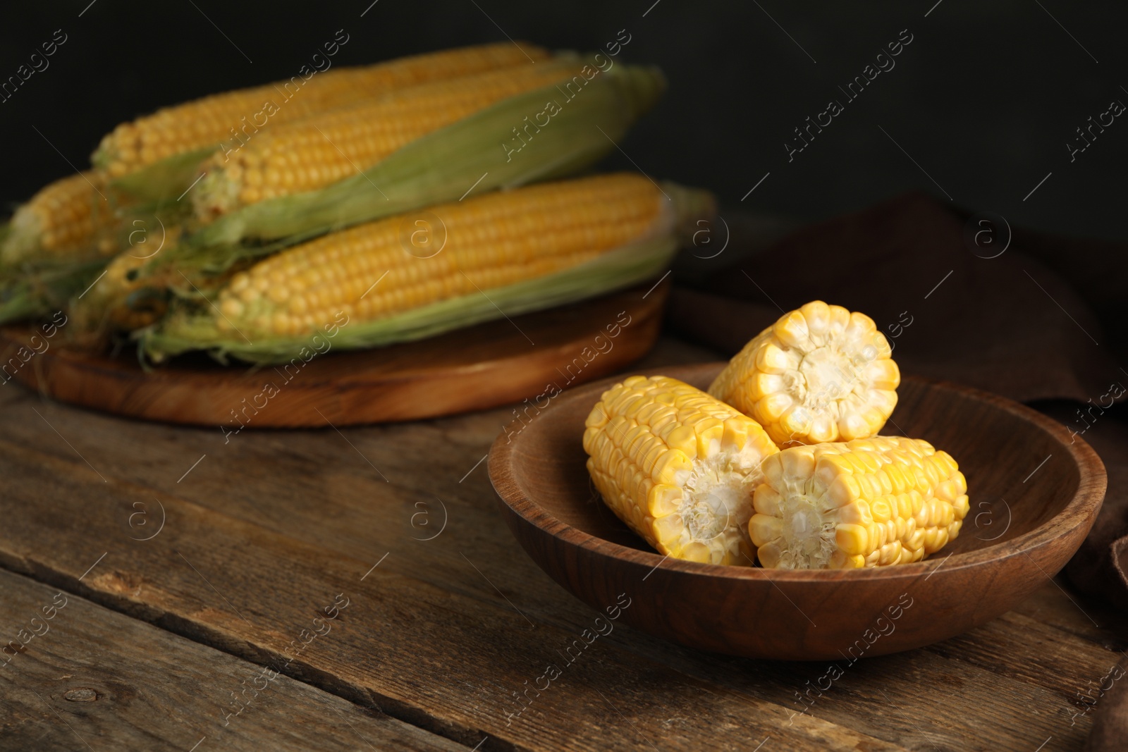 Photo of Tasty sweet corn cobs on wooden table. Space for text