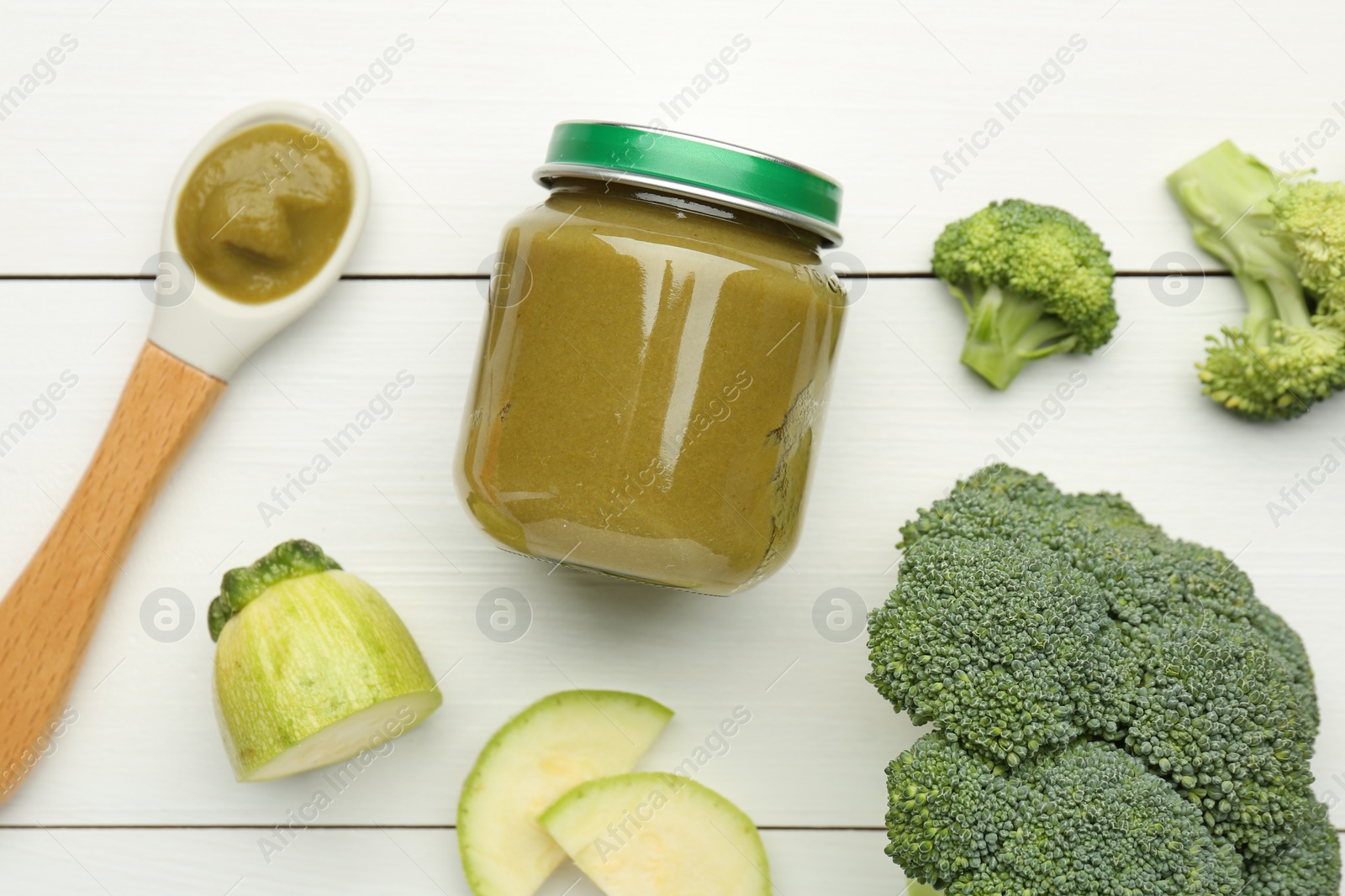 Photo of Tasty baby food in jar, broccoli and zucchini on white wooden table, flat lay