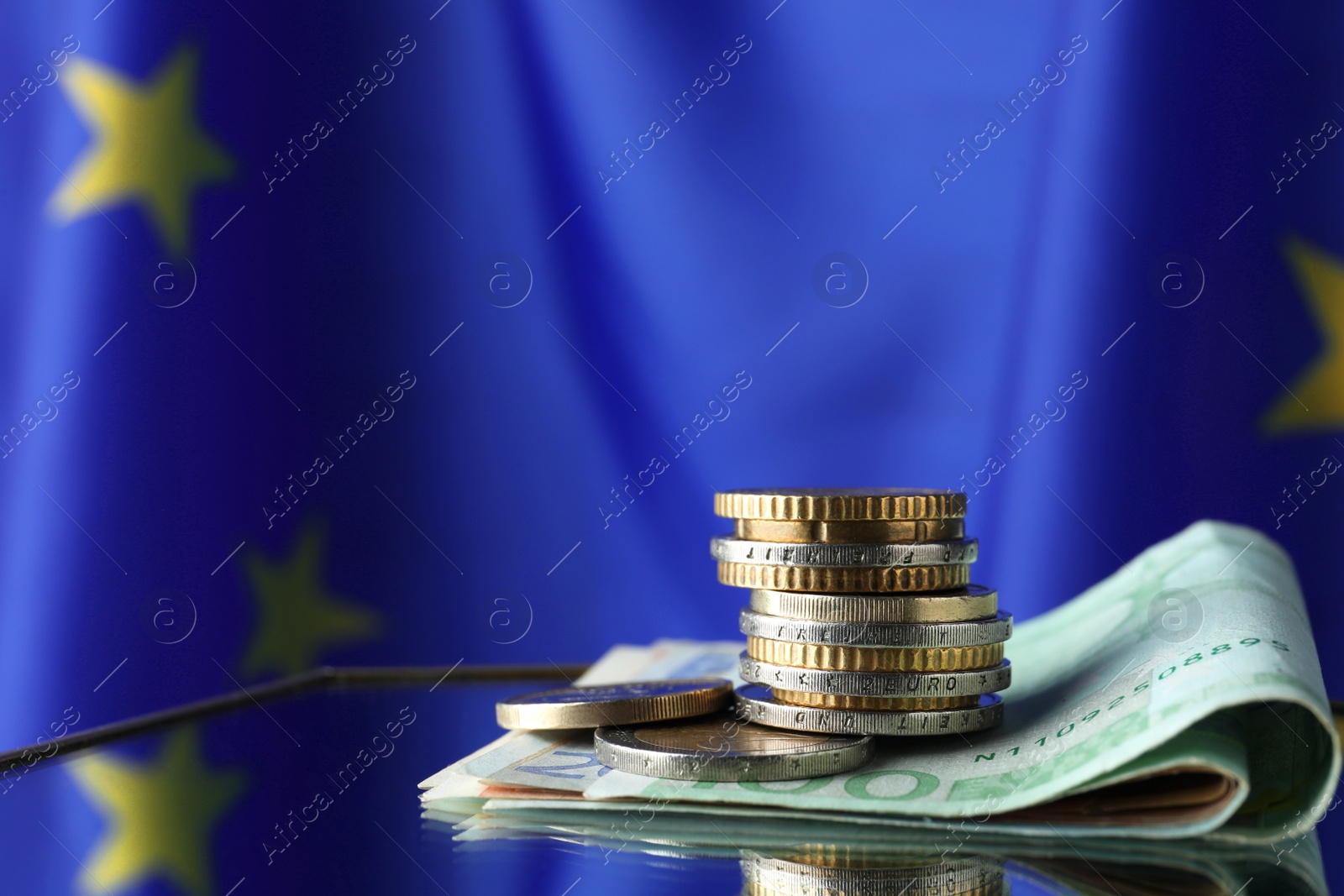 Photo of Coins and banknotes on table against European Union flag, space for text