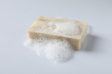 Photo of Soap with fluffy foam on white background