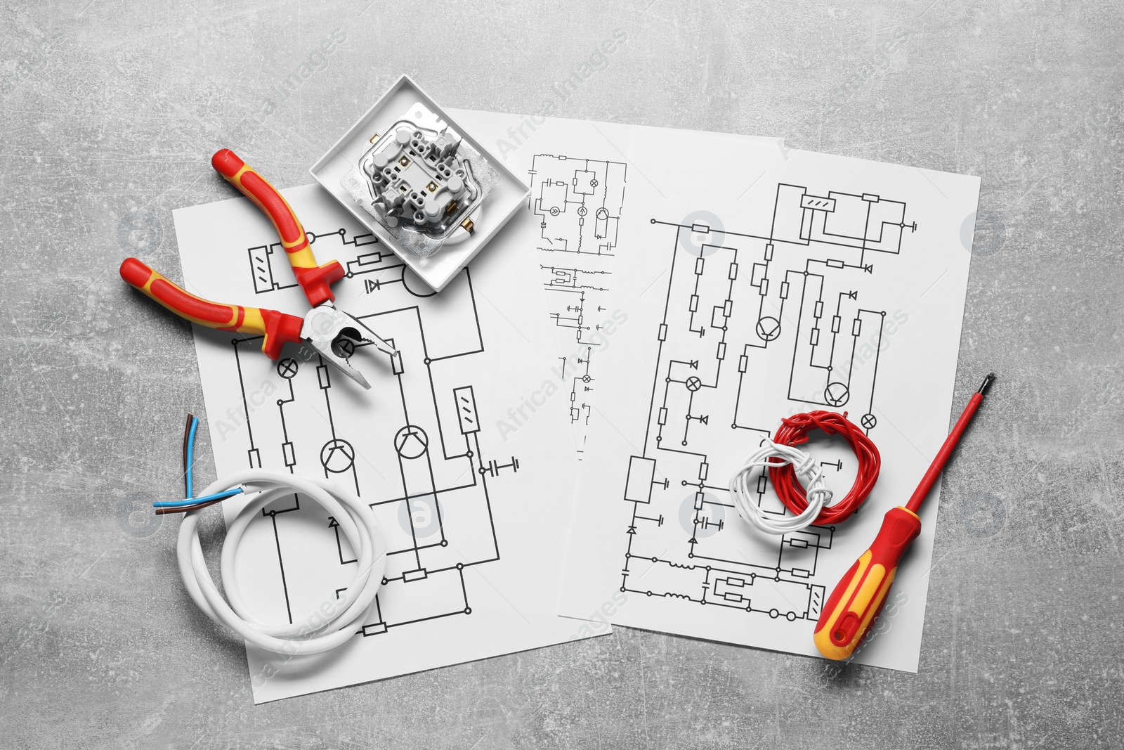 Photo of Wiring diagrams, wires and tools on grey table, flat lay