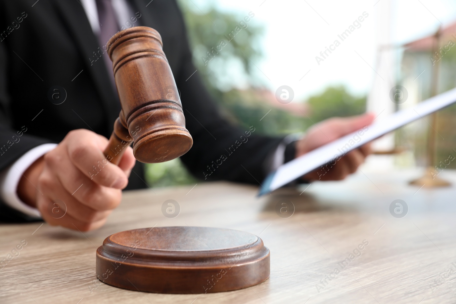 Photo of Judge with gavel at wooden table indoors, closeup. Criminal law