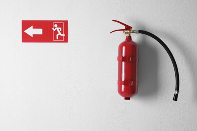 Photo of Fire extinguisher and emergency exit sign on white wall