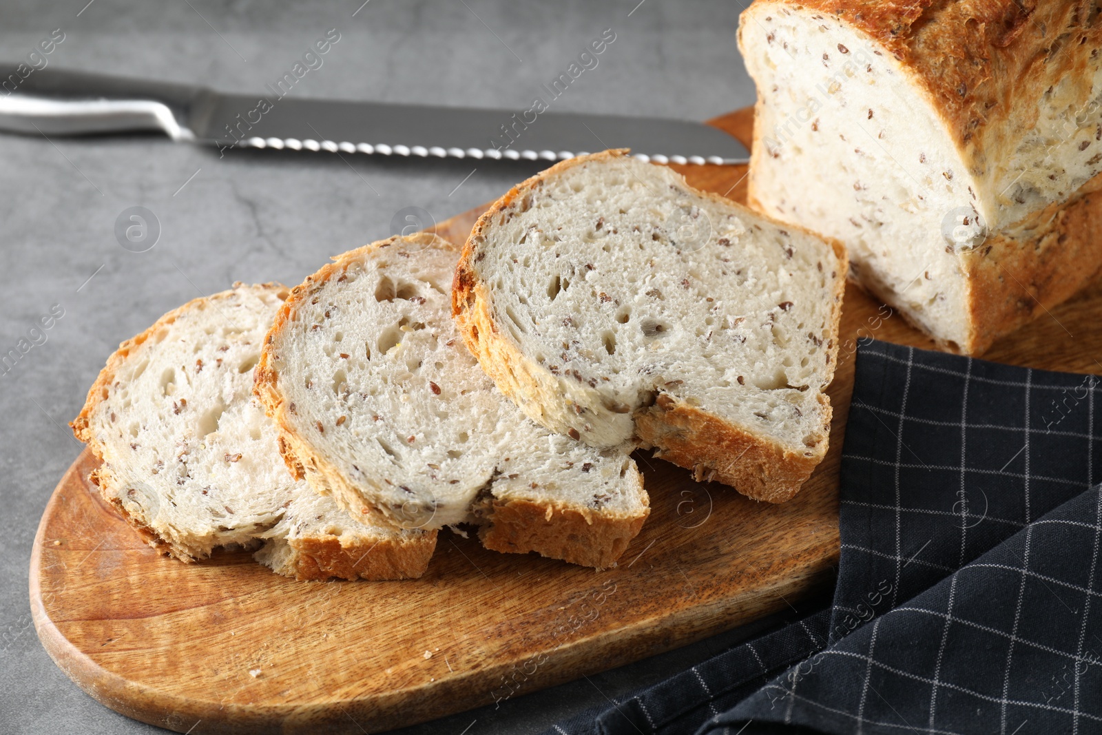 Photo of Freshly baked cut sourdough bread and knife on grey table, closeup