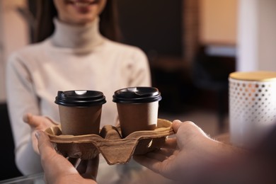 Photo of Barista giving takeaway coffee cups to client in cafe, closeup