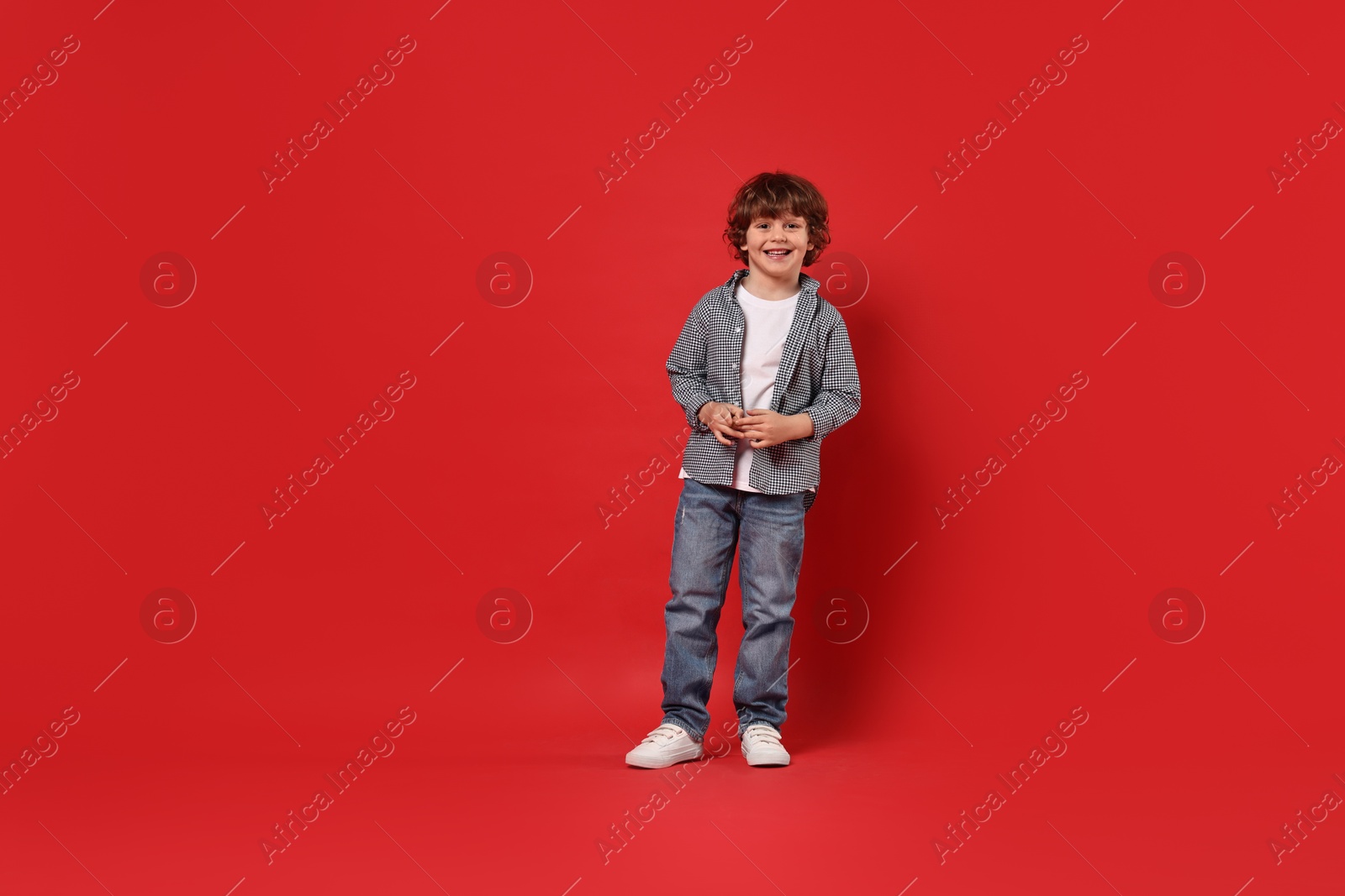 Photo of Happy little boy dancing on red background. Space for text