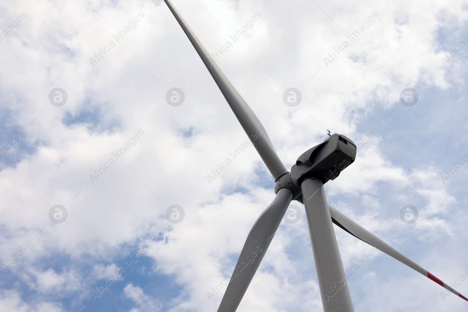 Photo of Modern wind turbine against cloudy sky, closeup. Alternative energy source