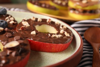 Photo of Fresh apples with nut butter, chocolate chips and nuts on table, closeup